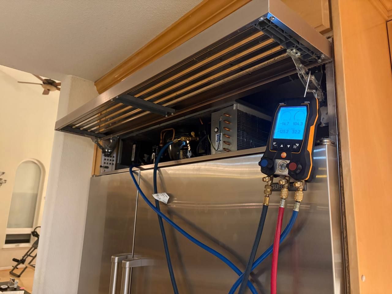PFC technician checking refrigerant pressure on a built-in refrigerator